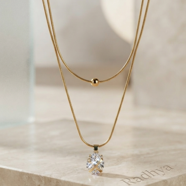 Layered gold snake chain with solitaire pendant.