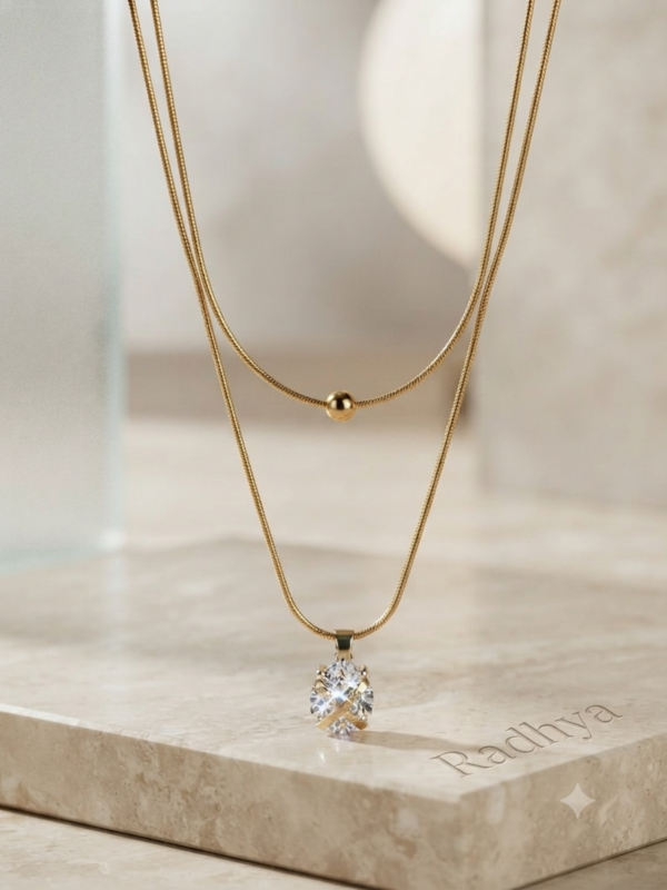Layered gold snake chain with solitaire pendant.