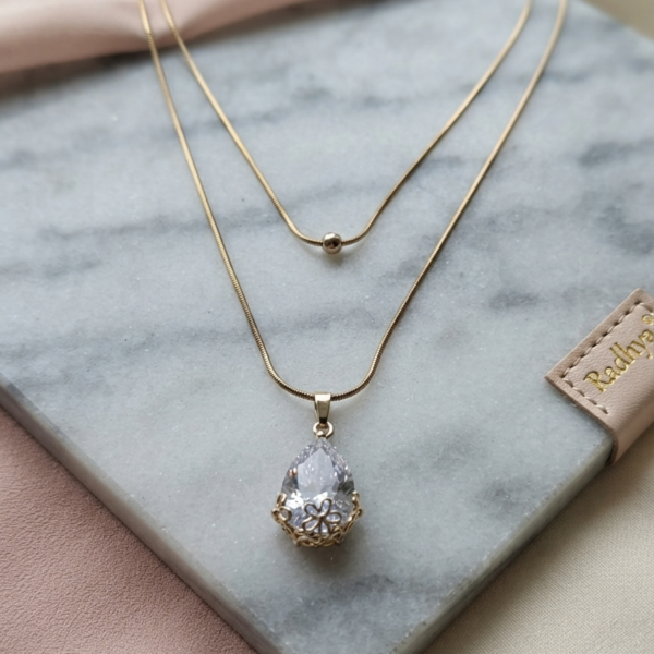 Layered gold snake chain with solitaire pendant.