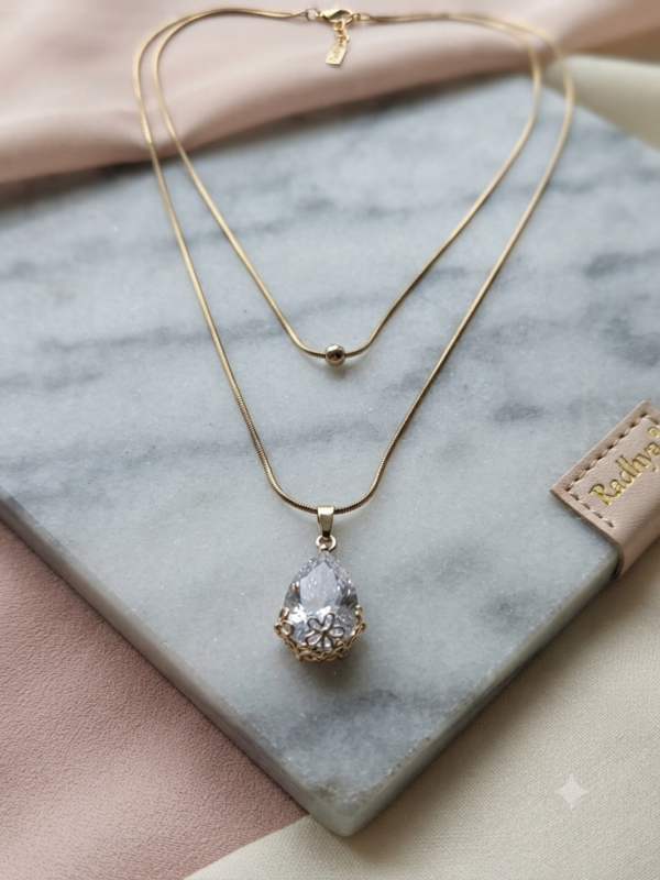 Layered gold snake chain with solitaire pendant.