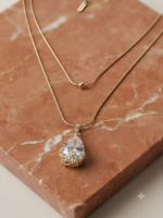 Layered gold snake chain with solitaire pendant.