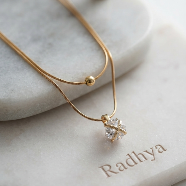 Layered gold snake chain with pear solitaire pendant.